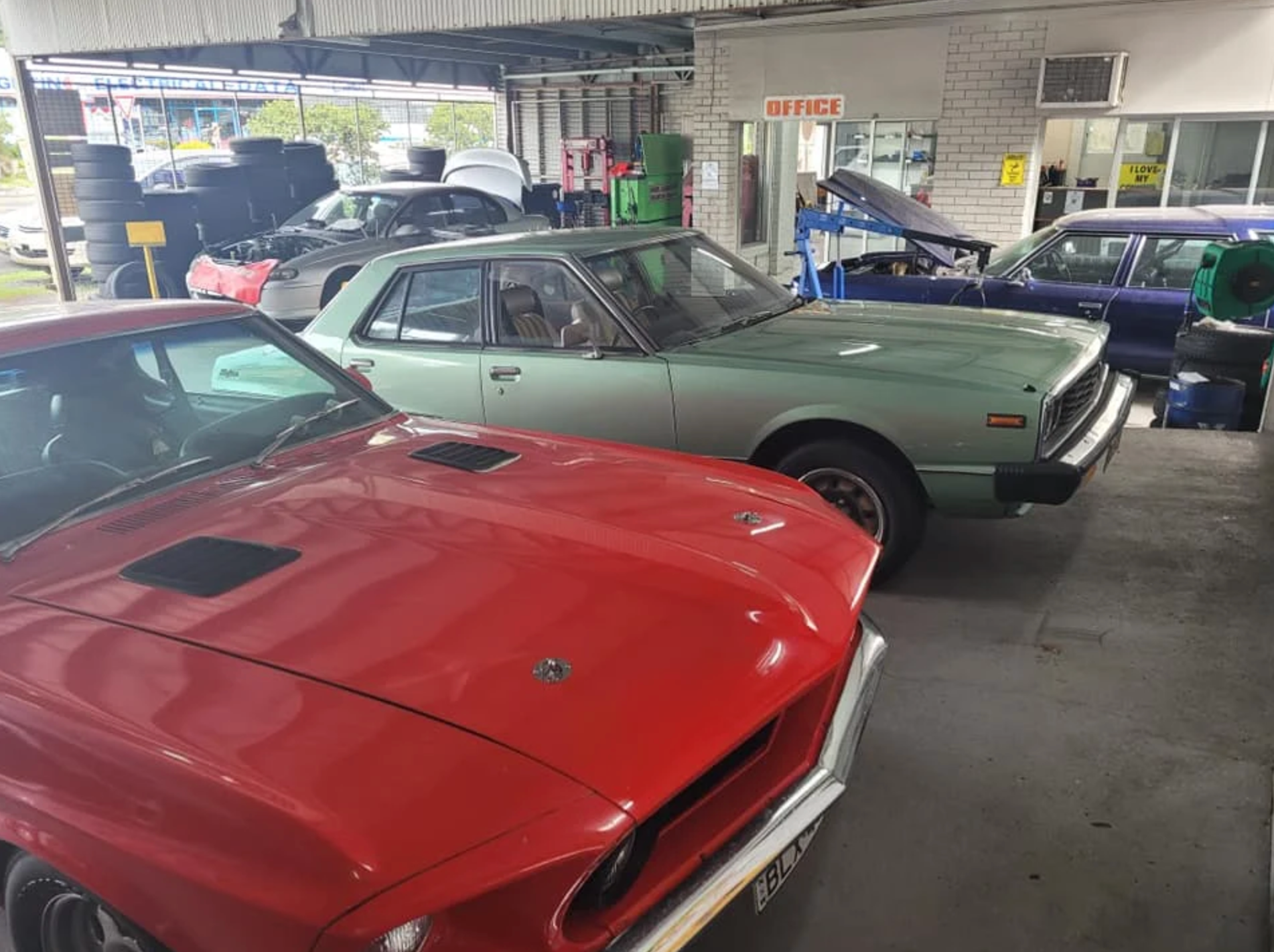 A red and lime green classic cars are parked in a workshop side by side — East Lismore Automotive in  East Lismore, NSW