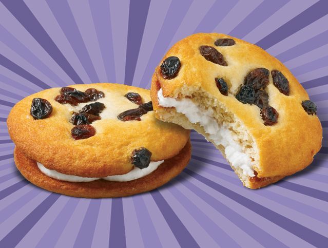 Two cookies with raisins and whipped cream on a purple background