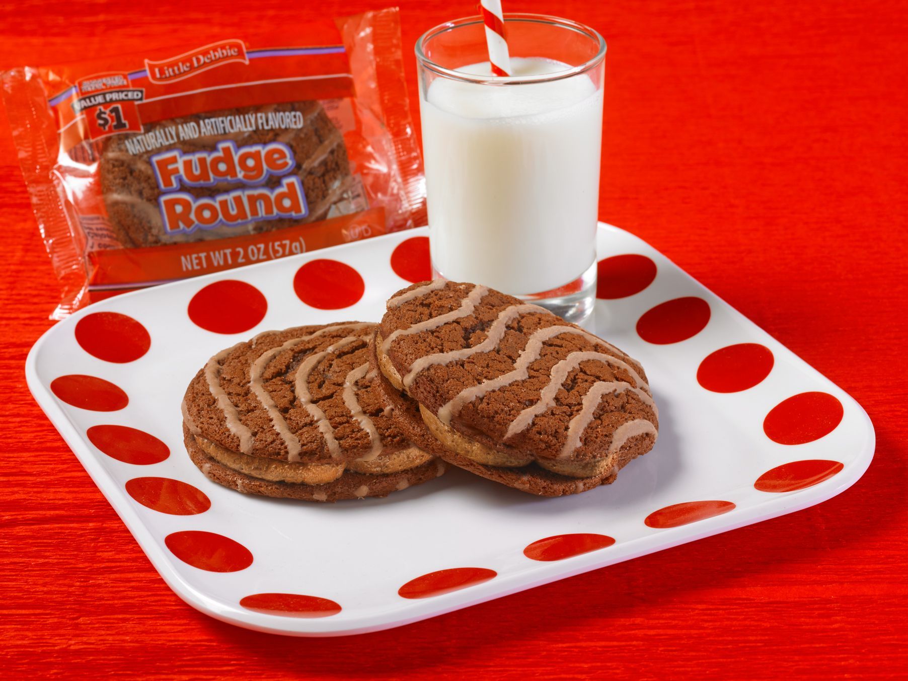 Two fudge round cookies on a plate next to a glass of milk