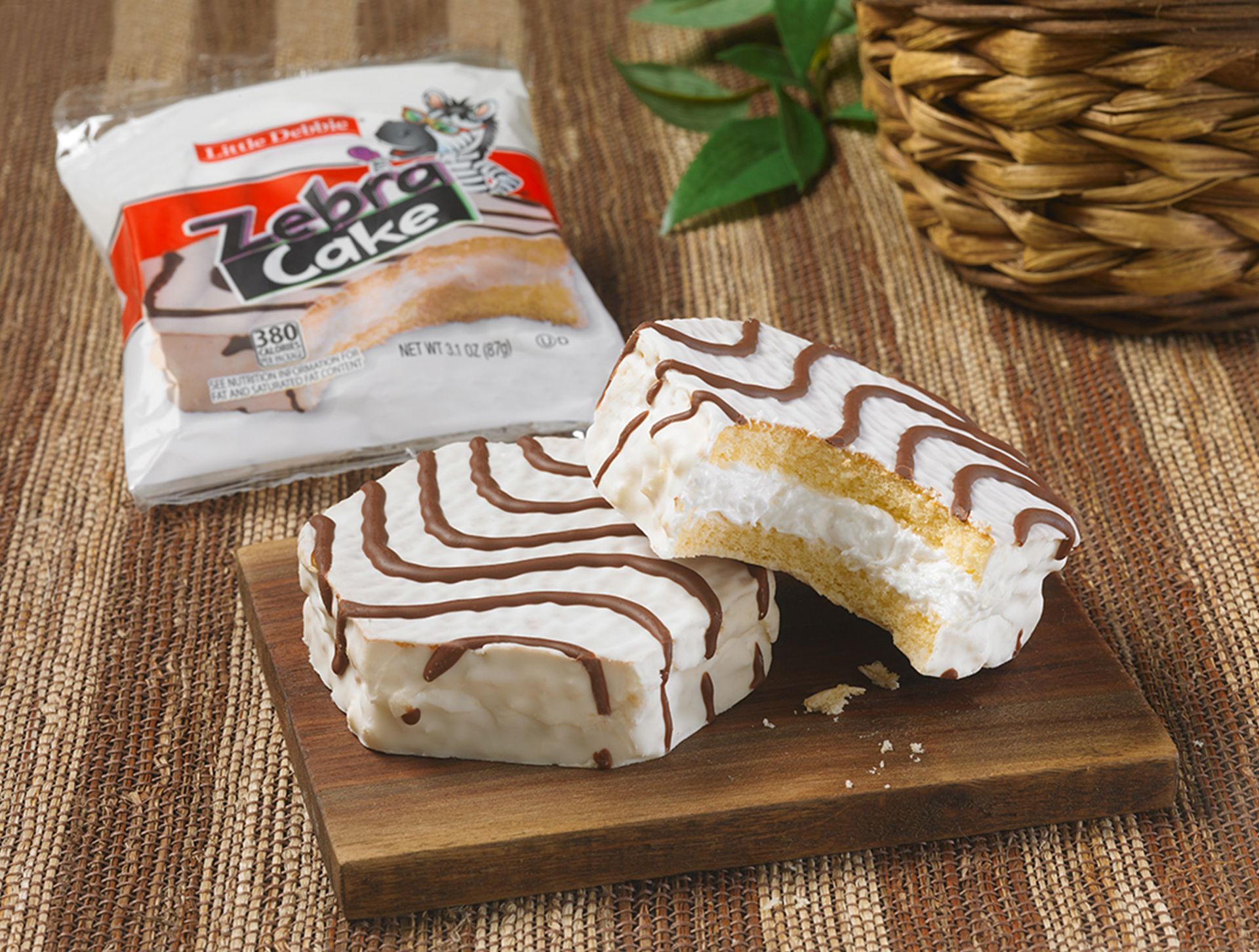 two single serve zebra cakes on a wooden board by a wrap