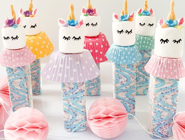 A group of unicorn marshmallows sitting on top of cupcake liners on a table.