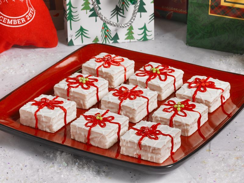 a red plate of fancy cakes decorated as christmas presents