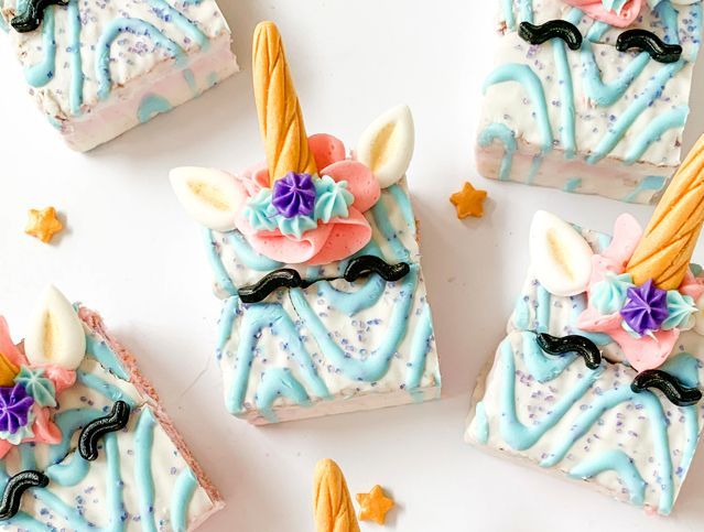 A group of unicorn treats decorated with frosting and sprinkles on a table.