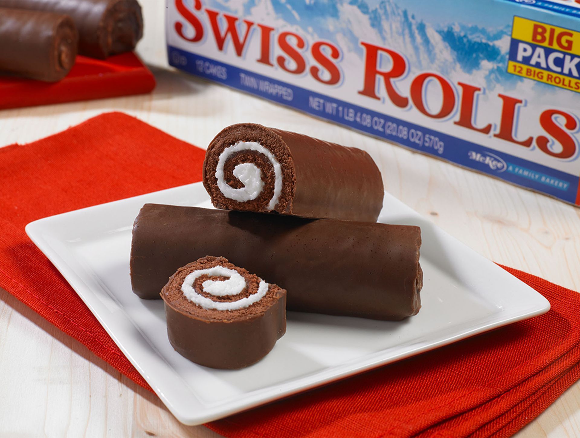 A white plate topped with swiss rolls next to a box of swiss rolls