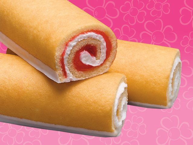 Two rolls of cake are stacked on top of each other on a pink background