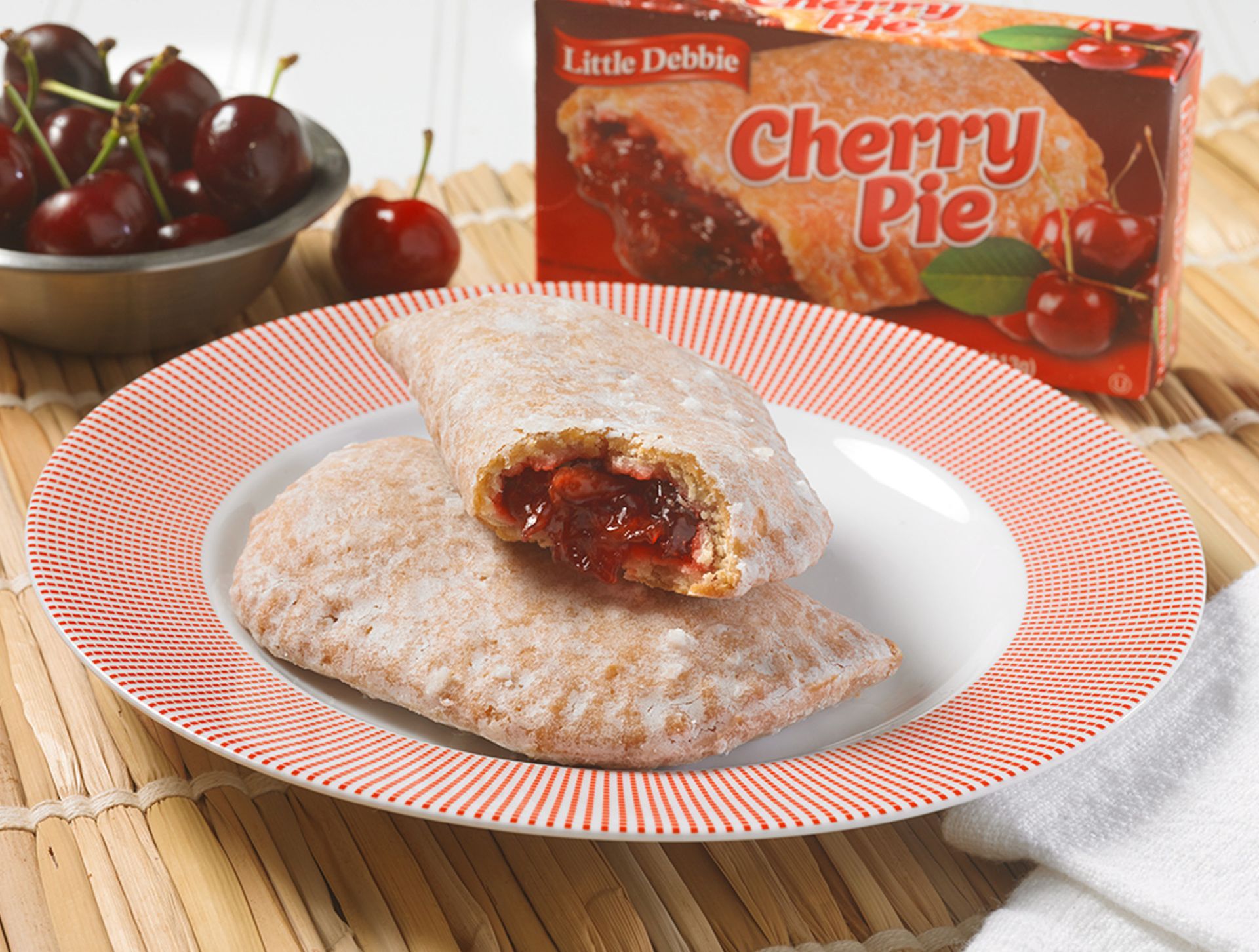 A pastry with cherries on a red checkered table cloth
