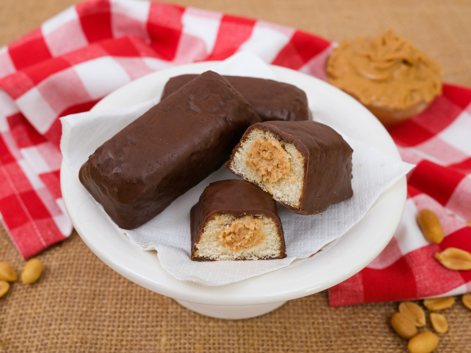 three nutty buddy cakes one a white plate with a red gingham napkin and one cake is broken in half to show the creme filling
