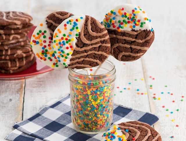 A jar filled with sprinkles and chocolate cookies on sticks