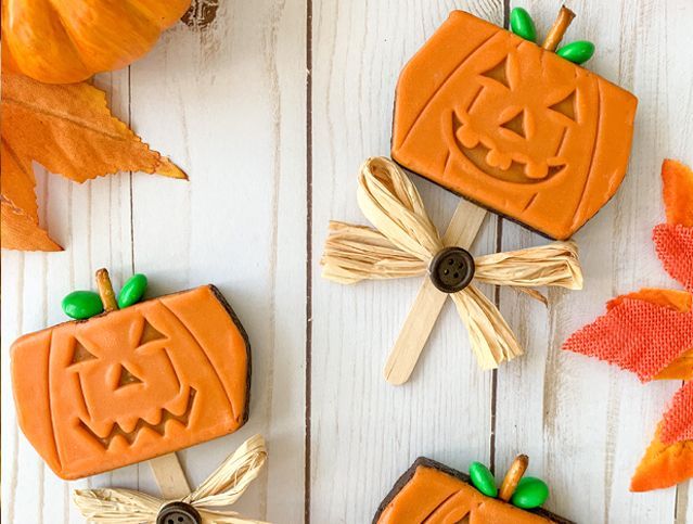 A wooden table topped with cookies in the shape of pumpkins.