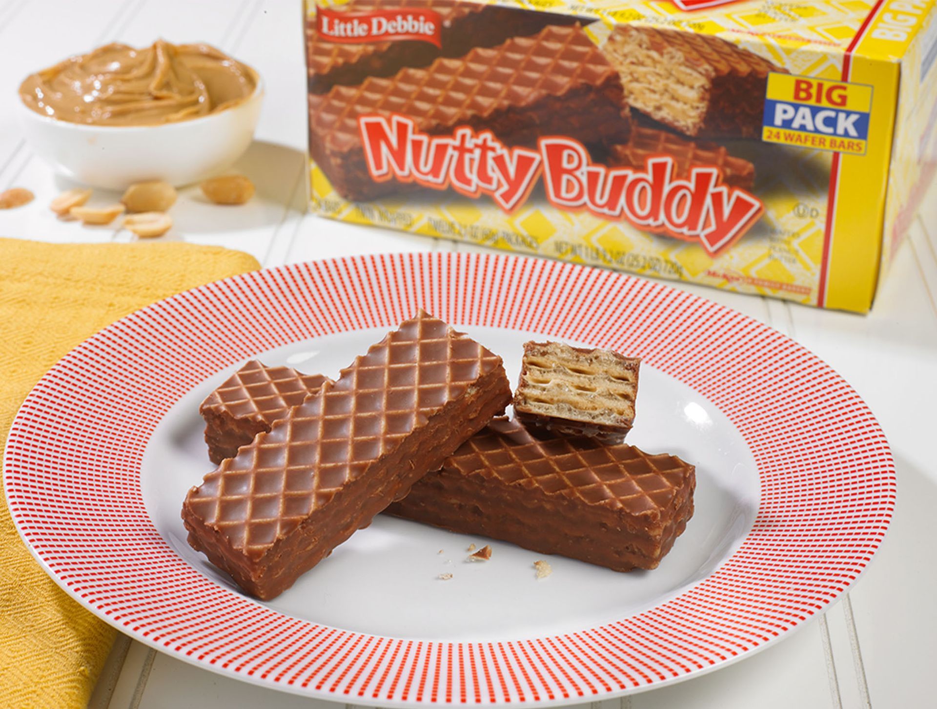 two nutty buddy wafer bars on a red and white plate next to a carton of big pack nutty buddy wafer bars