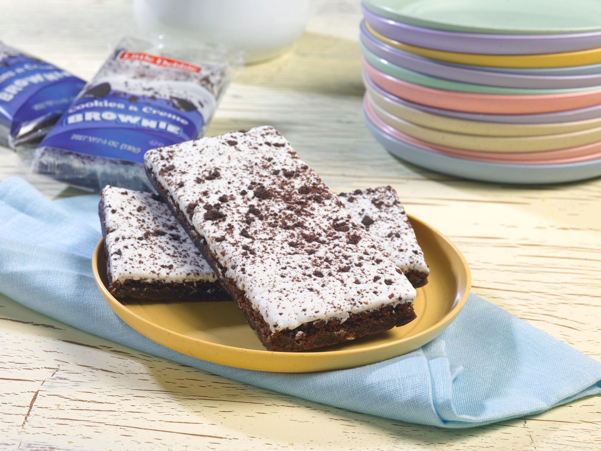 two cookies and creme brownies with a box in the background next to a glass of milk