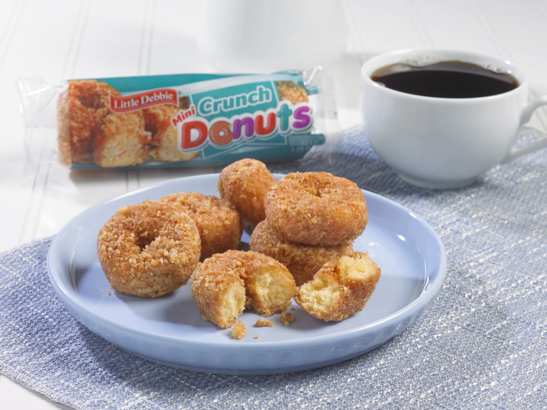 plate of single serve crunch mini donuts next to coffee and a wrapped one