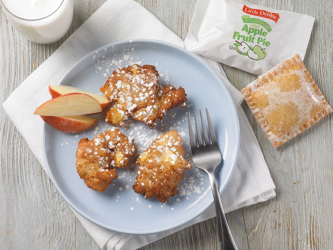 A blue plate topped with apple fritters and a fork on a table.