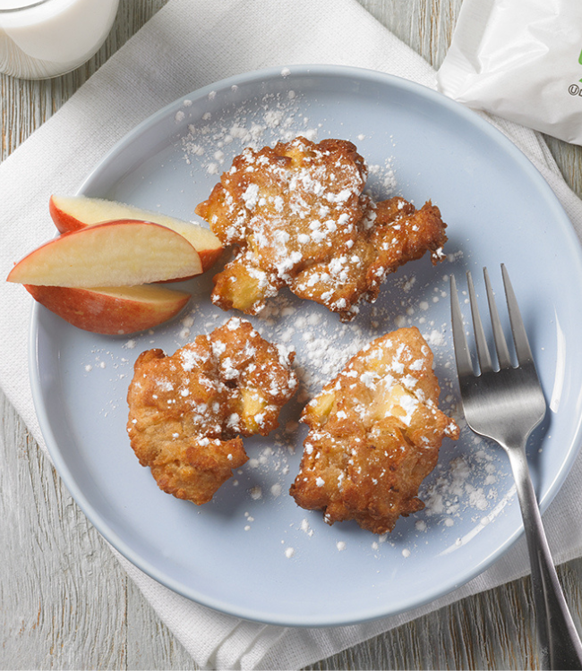 A blue plate topped with apple fritters and a fork on a table.