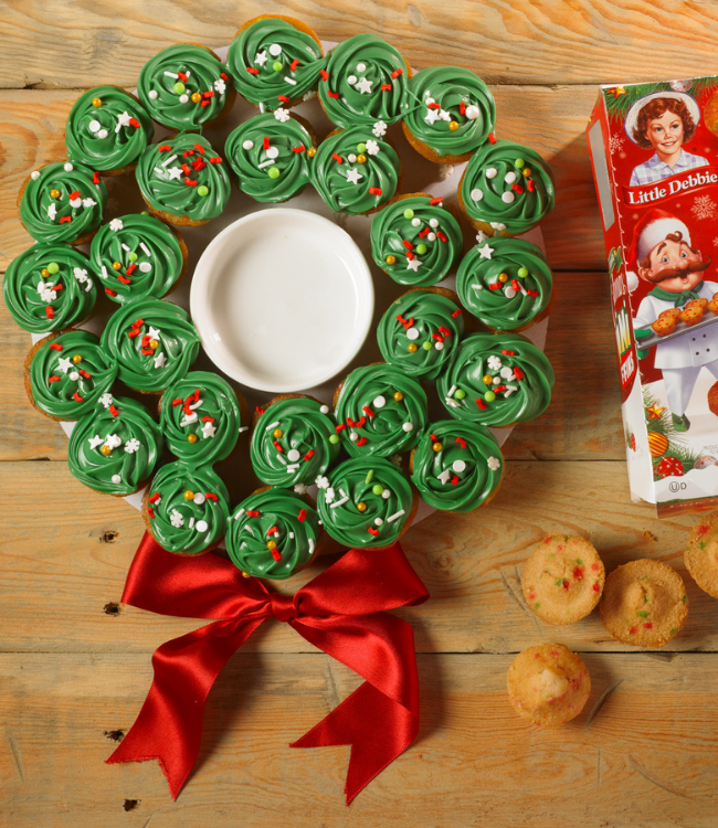 christmas mini muffins decorated with green frosting and sprinkles to form a wreath-shaped dessert