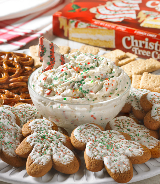 A bowl of dip is surrounded by gingerbread cookies and pretzels.