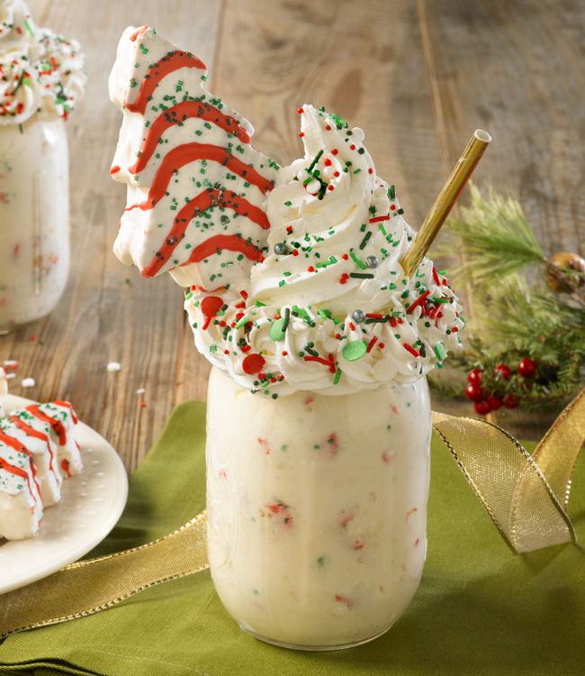 christmas tree cake milkshake topped with whipped creme and sprinkles