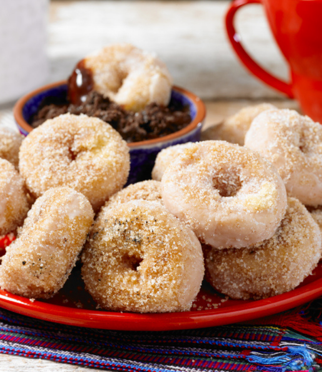 A red plate topped with churro style donuts and a cup of coffee.