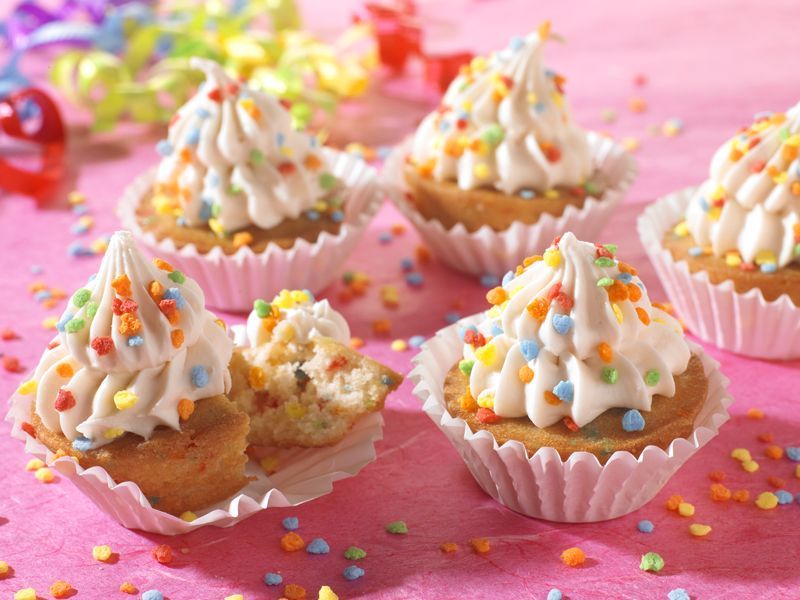 Cupcakes with frosting and sprinkles on a pink table
