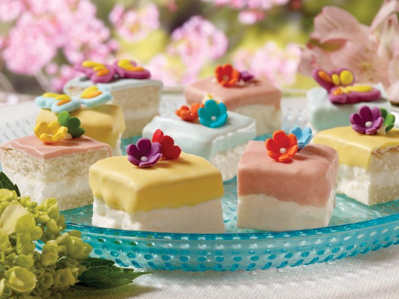 A blue plate topped with small cakes with flowers on them