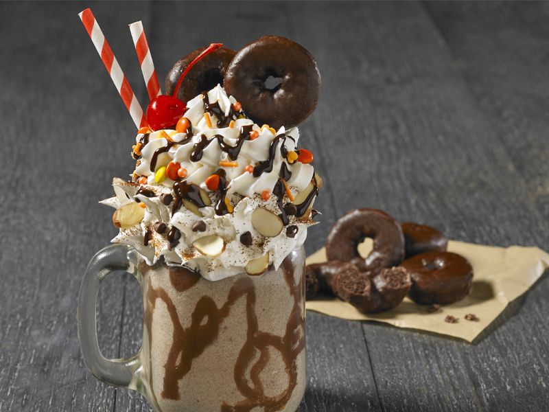fudge round mini donuts as a milkshake topped with whipped cream, almonds, candies and a cherry