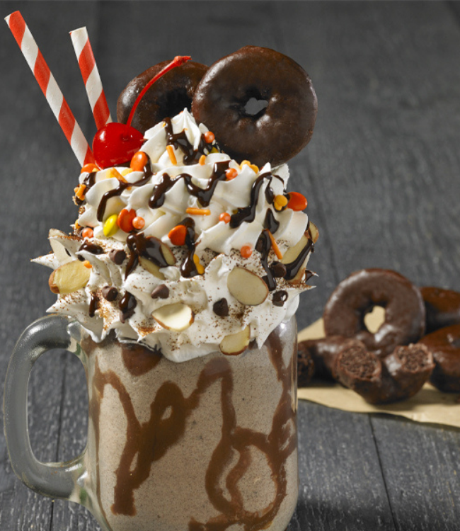 fudge round mini donuts as a milkshake topped with whipped cream, almonds, candies and a cherry