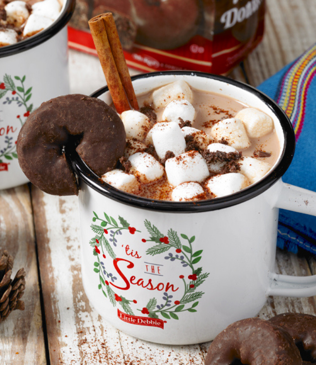 A cup of hot chocolate with marshmallows and a donut in it