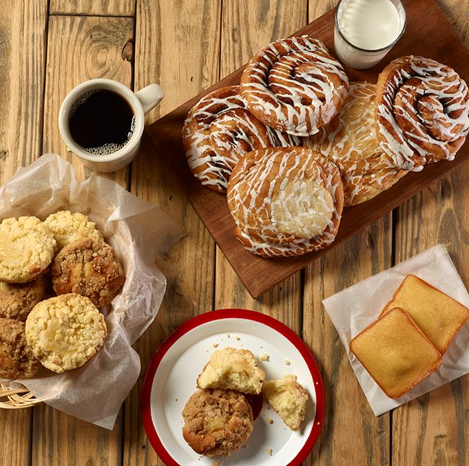 assorted pastries on a wooden cutting board next to a cup of coffee