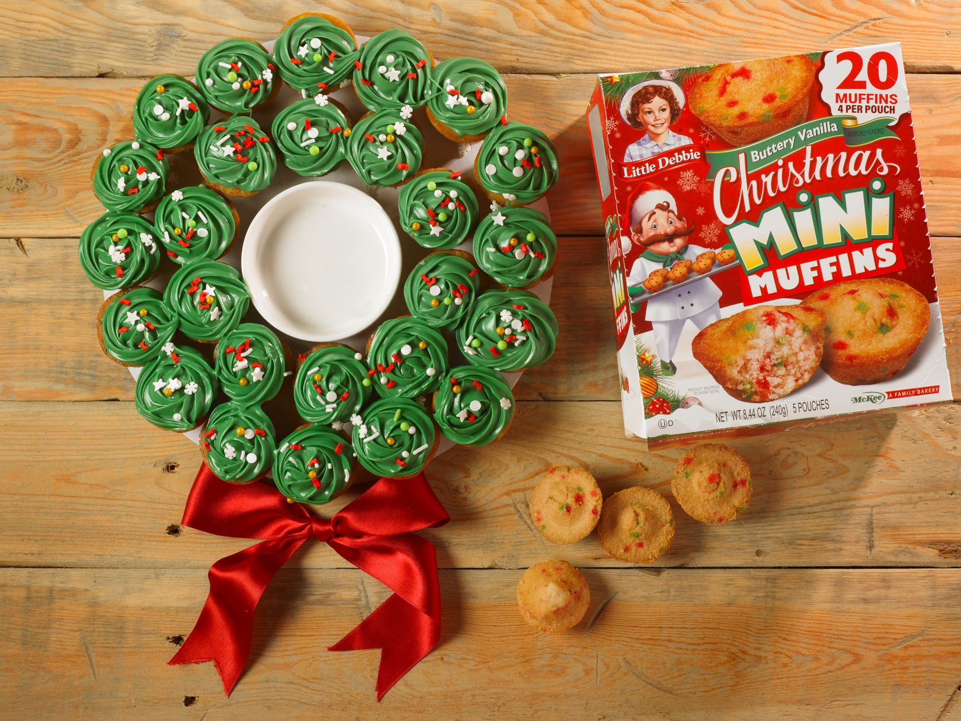 christmas mini muffins decorated with green frosting and sprinkles to form a wreath-shaped dessert