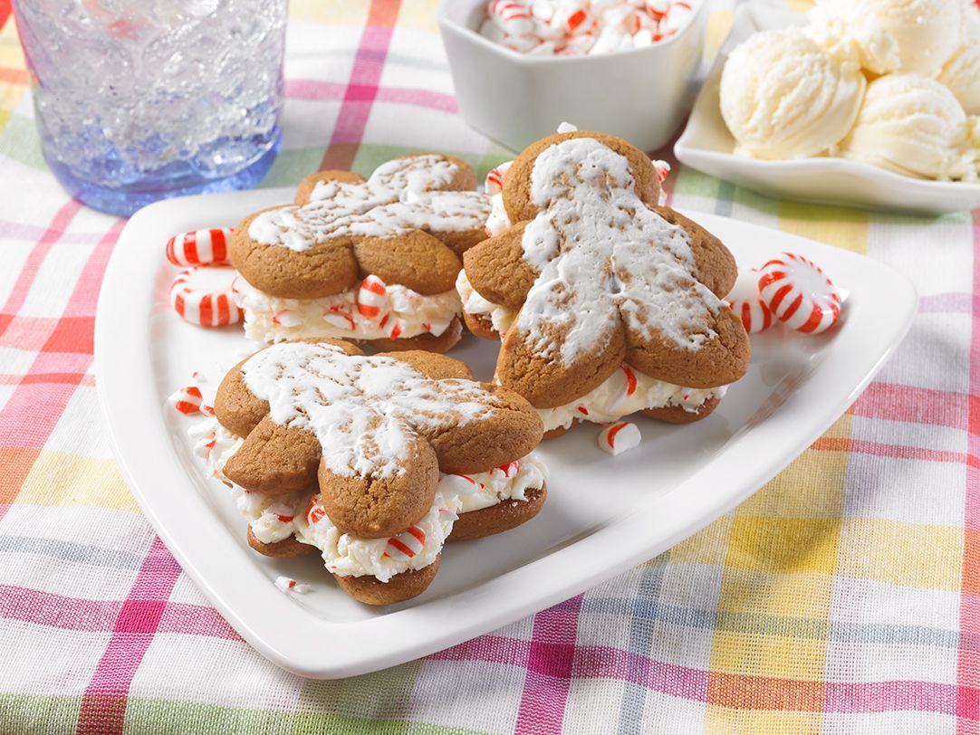 A white plate topped with gingerbread men ice cream sandwiches and peppermint candy