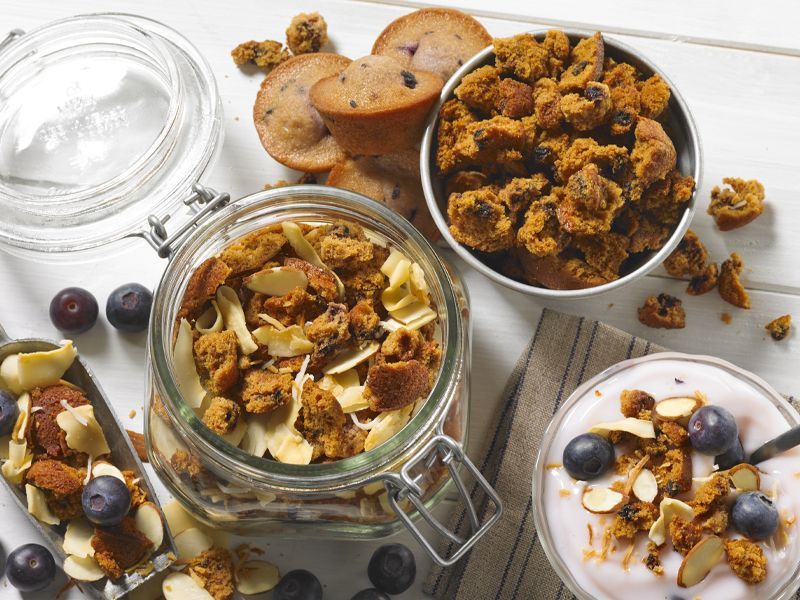 A jar of granola and a bowl of yogurt are on a table.