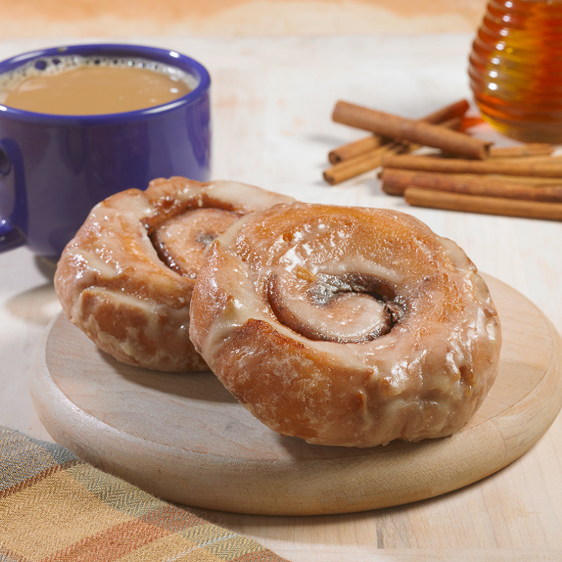 two single serve sticky buns on a plate by coffee