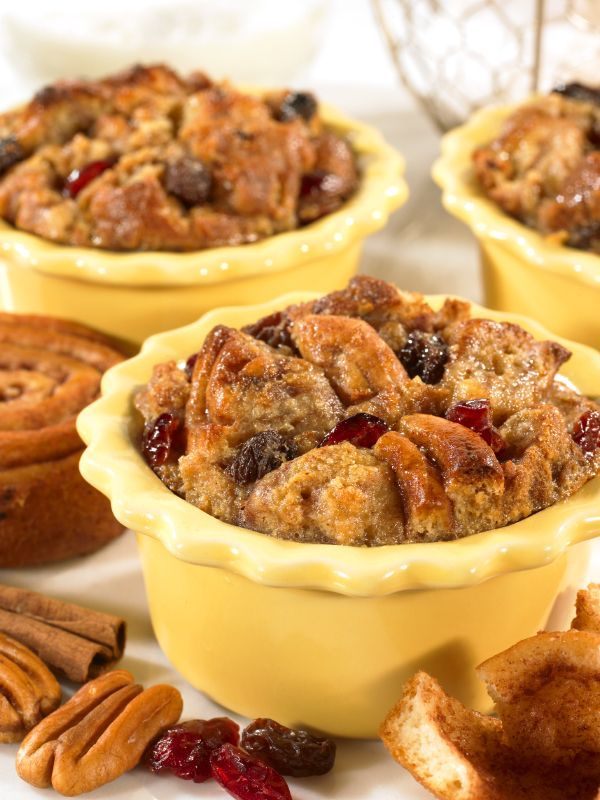 Three bowls of bread pudding with cranberries and pecans on a table.