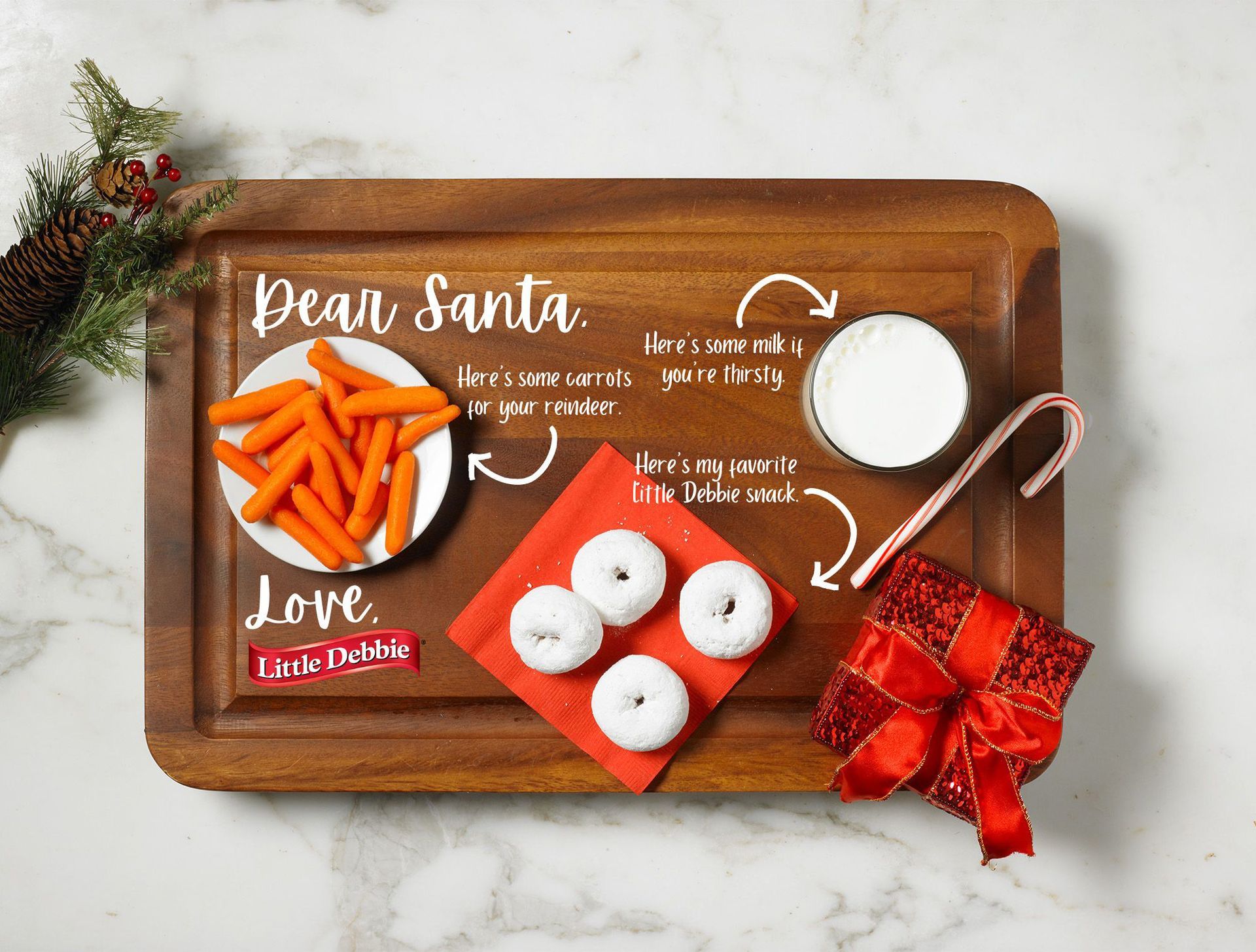 A wooden tray with a plate of carrots and donuts on it.