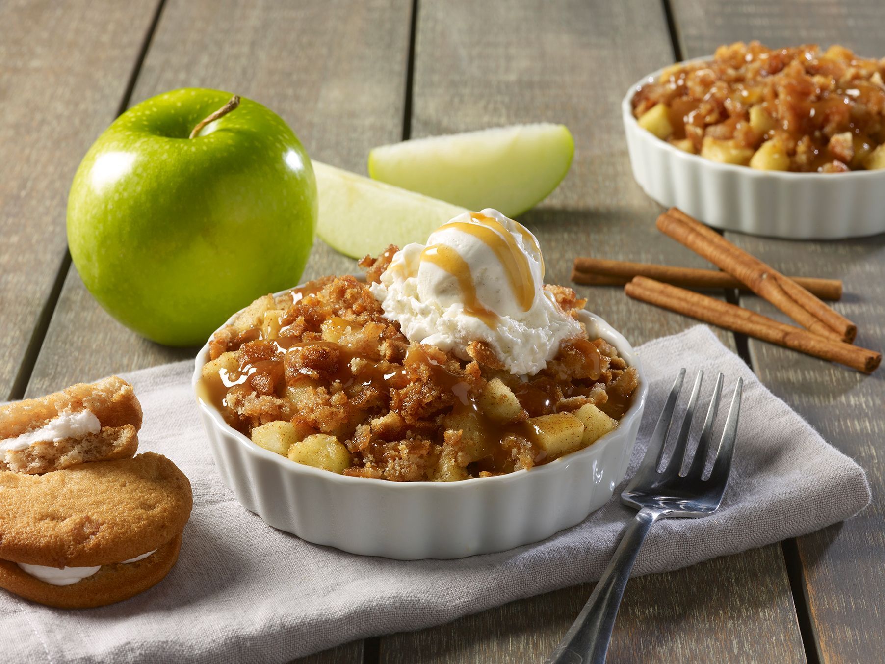 A bowl of apple crisp with ice cream and caramel sauce