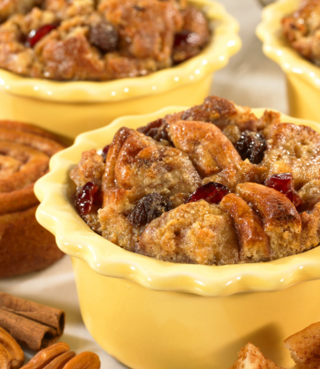 Three bowls of bread pudding with cranberries and pecans on a table.