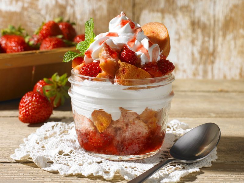 A strawberry shortcake dessert in a mason jar with whipped cream and strawberries.