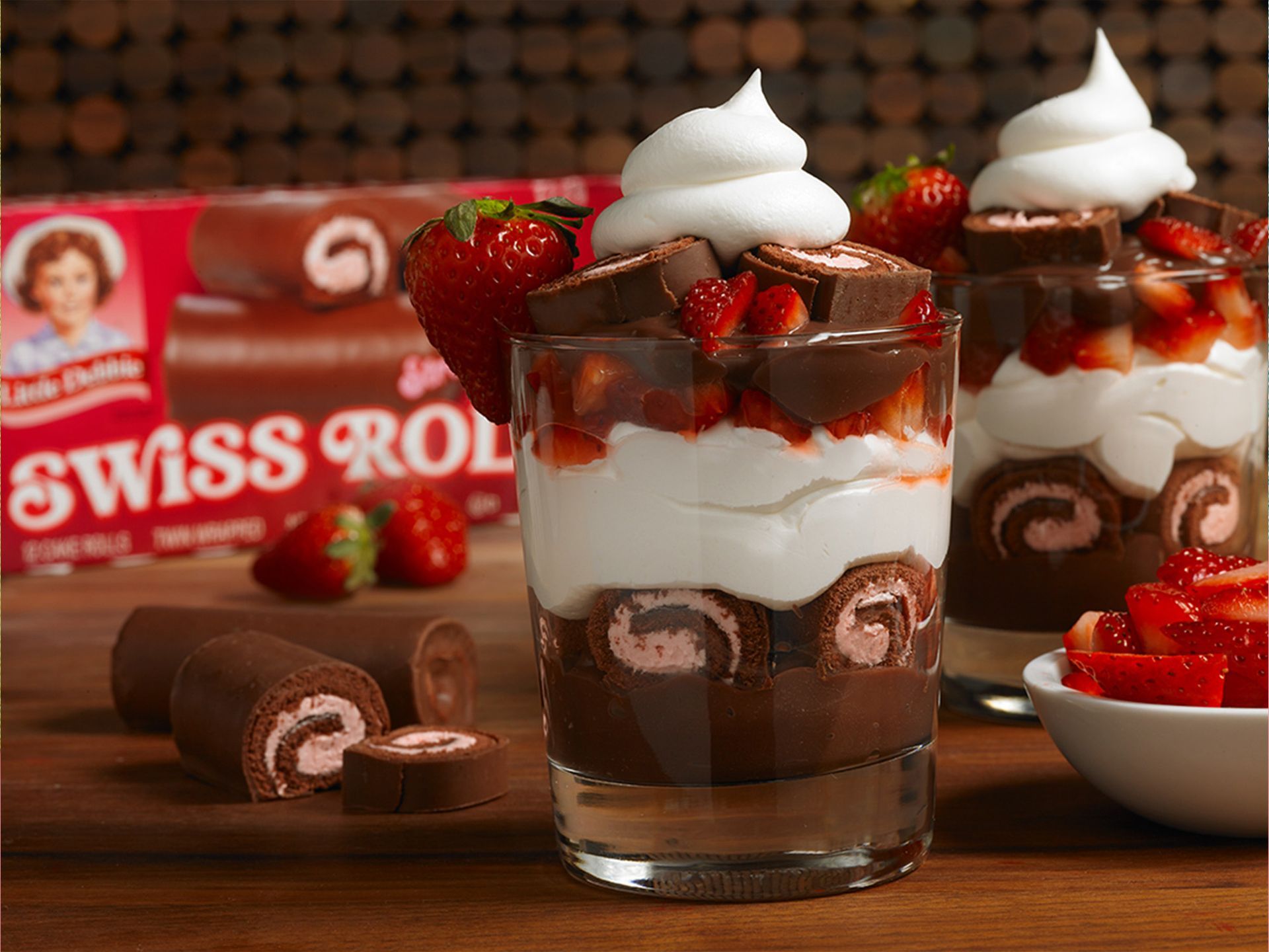 A swiss roll dessert with strawberries and whipped cream in a glass