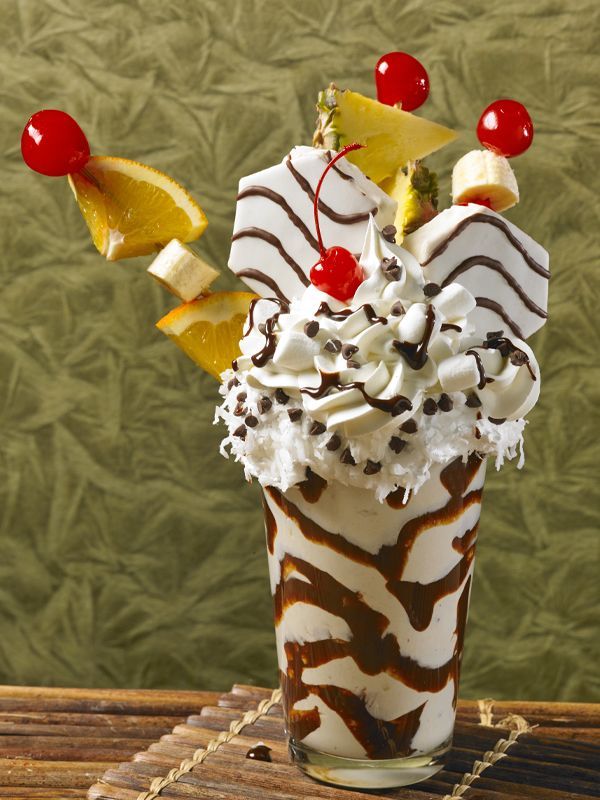 A milkshake with whipped cream and fruit on top