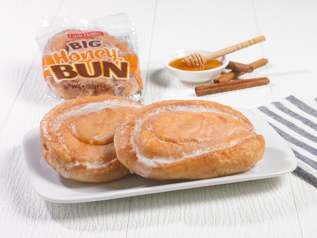 two single serve honey buns on a white plate next to a wrapped one