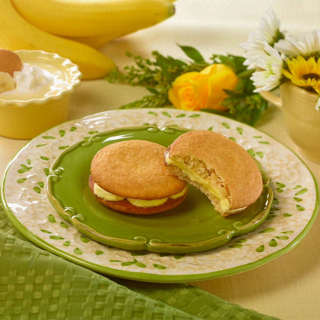 two banana puddin creme pies on a green plate with one missing a bite