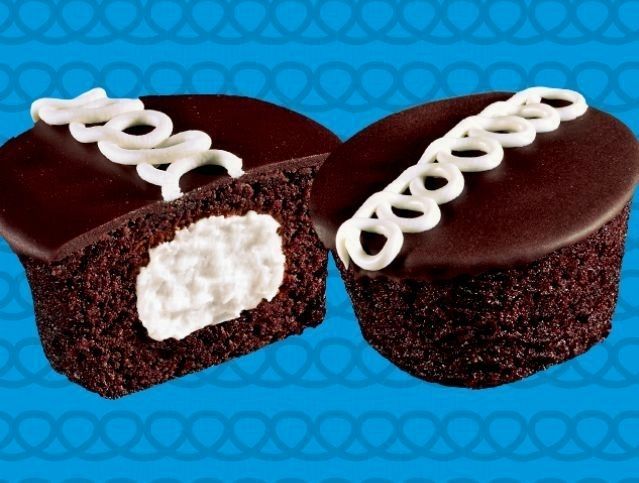 Two chocolate cupcakes with white frosting on a blue background