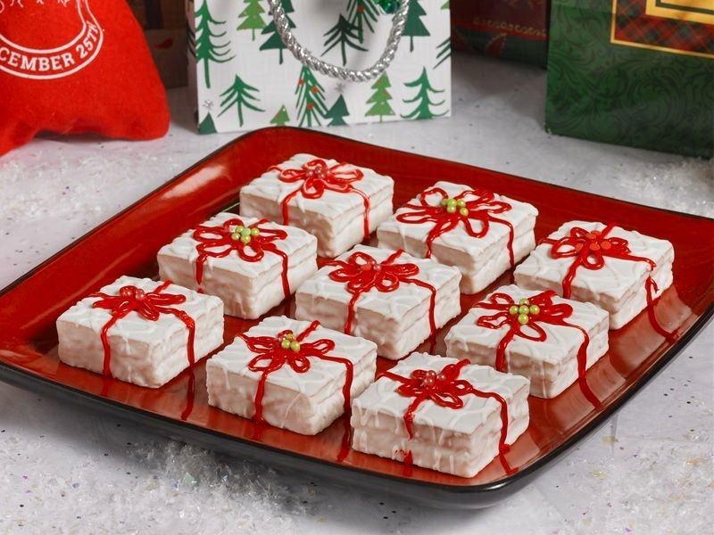 a red plate of fancy cakes decorated as christmas presents