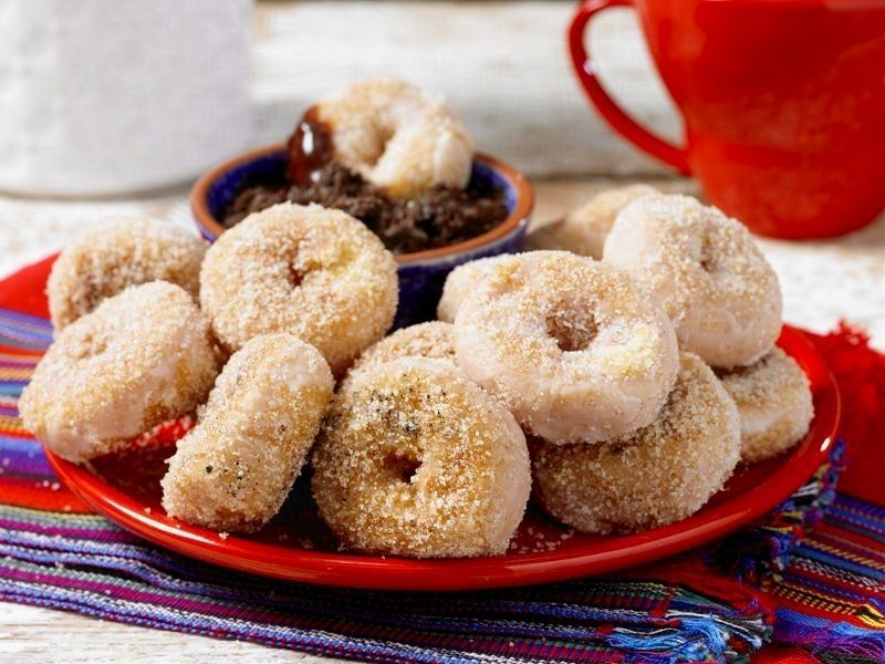 A red plate topped with churro style donuts and a cup of coffee.