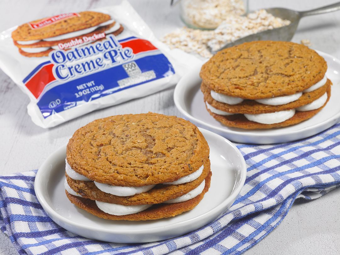 Two oatmeal creme pies are stacked on top of each other on plates.