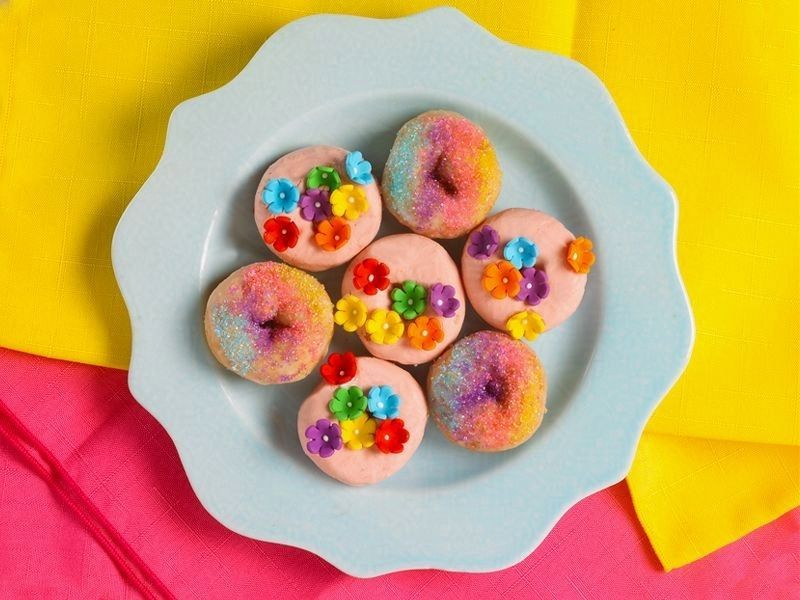 A plate of donuts decorated with flowers and sprinkles