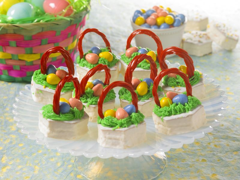 easter basket cakes decorated to look like easter baskets topped with licorice candy, candy eggs and green fr