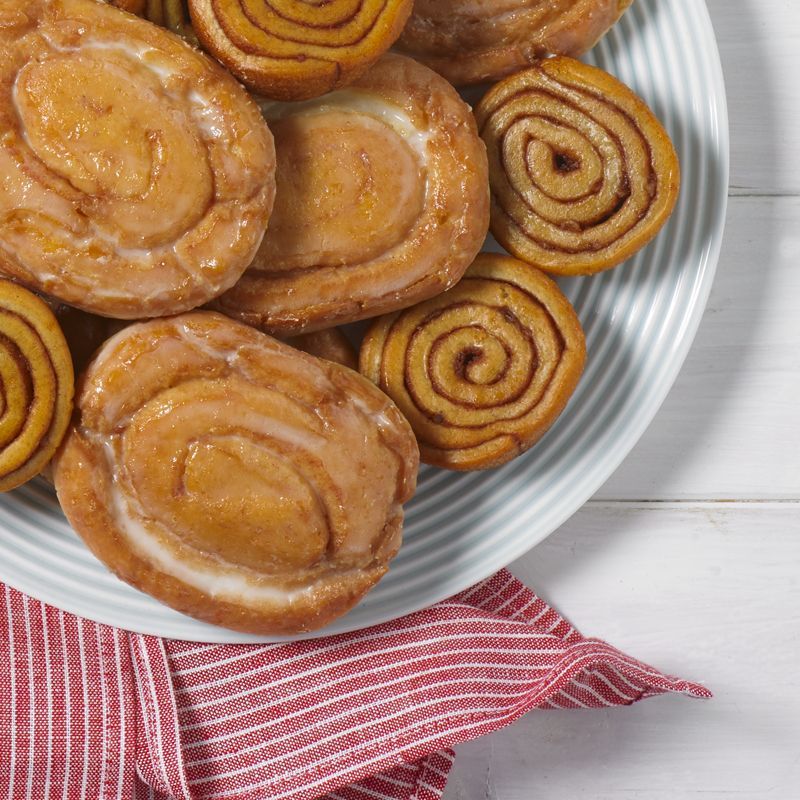a plate of honey buns and pecan spinwheels on a white plate with a red napkin and a white background