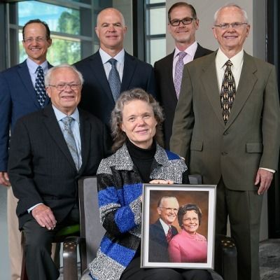 A woman is holding a framed picture of her husband and wife