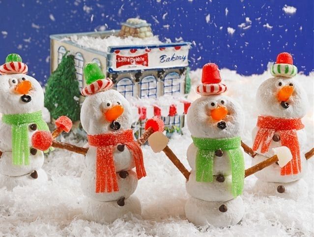 A group of snowmen are standing in the snow in front of a bakery